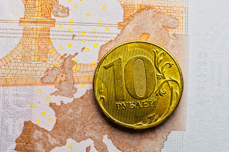 RUR golden coin lying over Euro banknote depicting raise of Russian economics ander sunctions and raise of inflation in EU.の写真素材