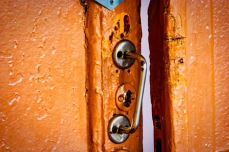Old-fashion russian door handle and old door painted in brown color. An intricate old-fashioned Russian door handle adds a touch of elegance to the aged brown painted door.の写真素材