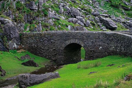 Old, stone bridge in green sceneryの写真素材