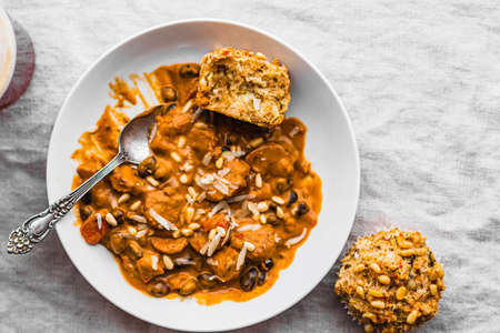 Red pepper & sausage soup in a white bowl with zucchini muffinsの写真素材