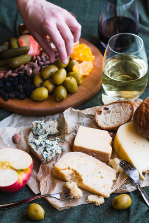 A hand reaching for food in a cheese board spreadの写真素材