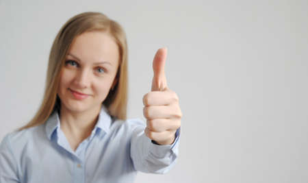 young woman shows thumb up. good, positive mark and result gesture from pretty girl. well done...