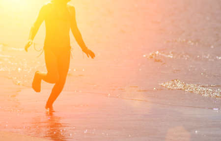 little kid runs at the shore against the sun