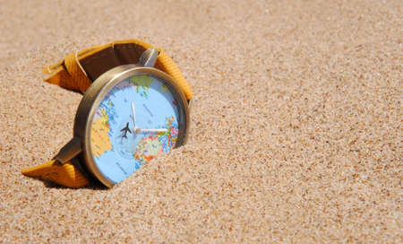 travel watch with a world map in the sand. vacation conceptの写真素材