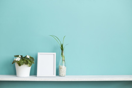 Modern room decoration with Picture frame mockup. White shelf against pastel turquoise wall with spider plant cuttings in water and violet.の写真素材