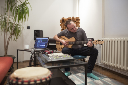 Professional musician recording electric guitar in digital studio at home. He is surrounded with...