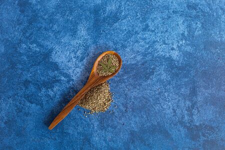 Hemp seeds on wooden scoop, dark blue backgroundl. Medicinal marijuana.の写真素材