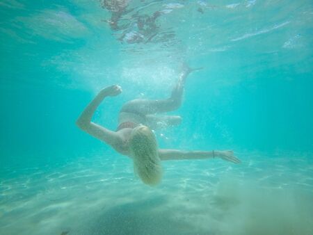 Under water photo of a woman in bikini diving in turquoise sea water.の写真素材