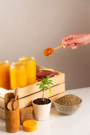 Three jars of CBD honey placed in a wooden crate. Around the crate are positioned a marijuana plant...