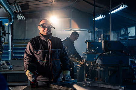 The handyman for grinding poses with a smile in the workshop with safety goggles.の写真素材