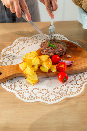 A close-up view of serving burgers on a wooden kitchen board, while on the sides there are side...