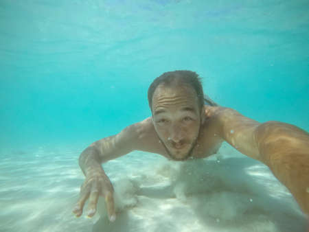 Under water photo of a man diving without equipment in turquoise sea water.の写真素材