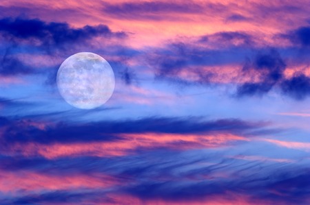 Moon clouds skies is a vibrant surreal fantasy like cloudscape with the ethereal heavenly full moon rising among the vibrant cloudscape.の写真素材