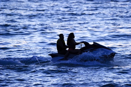 Jetski people is a couple riding a jetski silhouetted against the deep blue sea at evening time.の写真素材