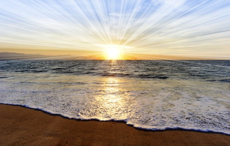 Ocean sunset sun rays is a brightly lit golden orange seascape with a burst of sun beams as a gentle...