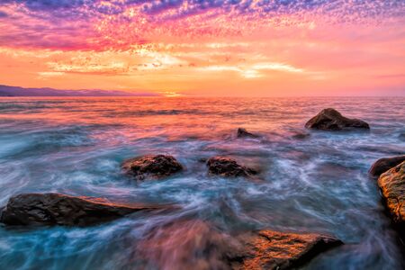 A Colorful Ocean Sunset Landscape as a Wave Comes to the Beach Shore