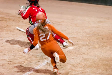 A Texas Longhorn Player is Sliding Into Home Plate Scoring A Run