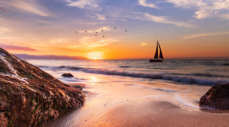 A Sailboat Is Sailing Along The Ocean With a Flock Of Birds Flying Overhead Against A Colorful...