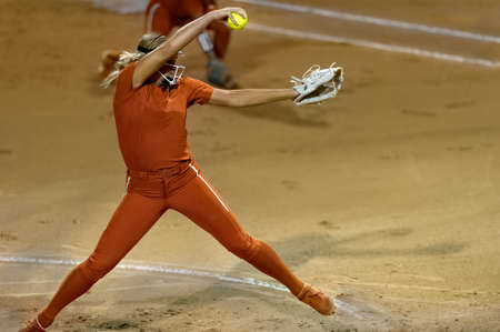 An Image Of A Softball Player Female Athlete Pitcher Is Winding Up To Deliver a Pitch To The Plateの写真素材
