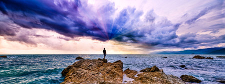 A Man Is Looking At An Ocean Sunset Towards An Ocean Sunset Light Beams In Banner Image Formatの写真素材