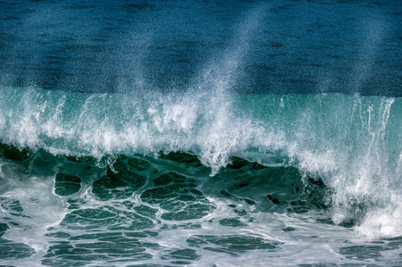 An Big Ocean Wave Is Breaking With White Spray At The Top