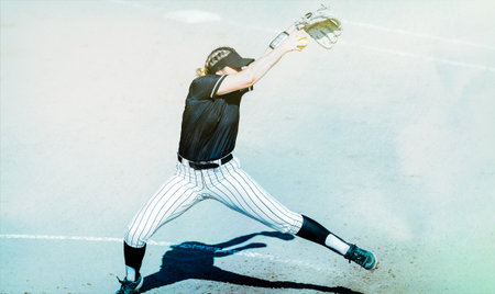 A Female Softball Player Is Pitching The Baseball In Full Windup
