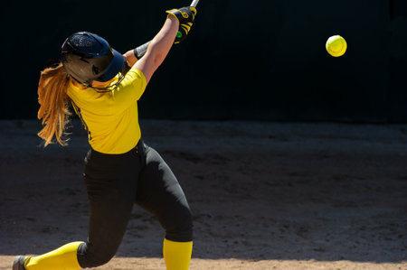 A Baseball Softball Player Is Swinging And Hitting The Ballの写真素材