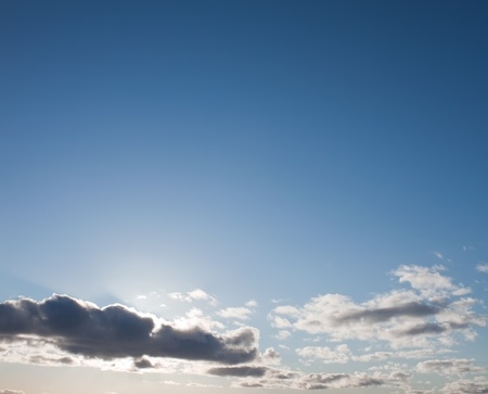 Sun lights on the blue sky with big cloudsの写真素材