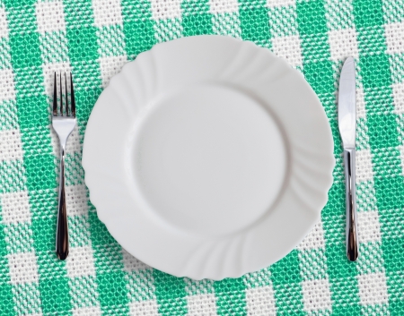 Plate with silverware on checquered green  backgroundの写真素材