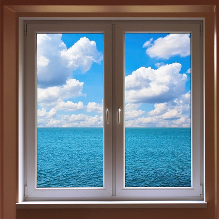 Windows with view to sea with cloudy sunny skyの写真素材