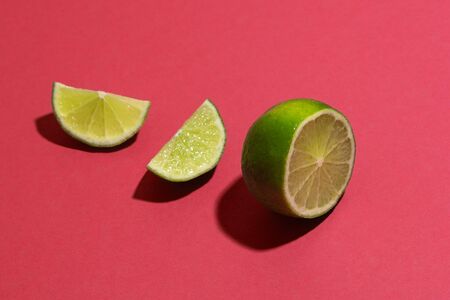One ripe lime sliced on parts on color surfaceの写真素材