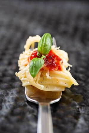 Pasta on fork with ketchup and basil leafの写真素材