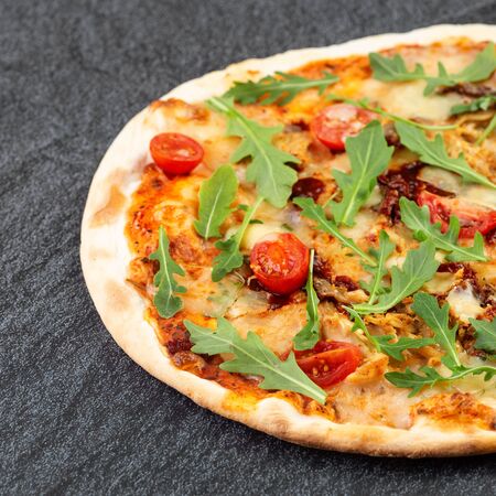 Juicy pizza on the table with cherry tomatoes and ruccolaの写真素材