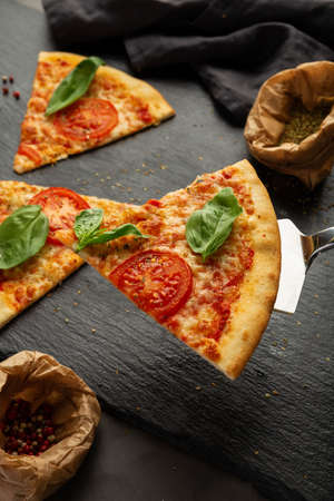 Piece of pizza on the table with ingredientsの写真素材