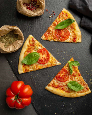 Pieces of pizza on the table with ingredientsの写真素材