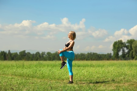 Beautiful sport woman doing stretching fitness exercise in city park at green grass. Yoga posturesの写真素材