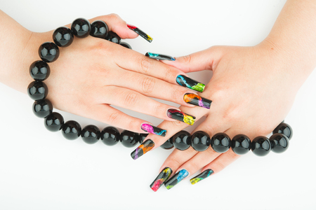 Female hands with beautiful manicure holding a large black beads on a white backgroundの写真素材