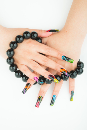 Female hands with beautiful manicure holding a large black beads on a white backgroundの写真素材