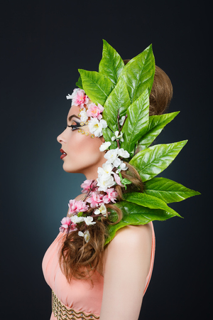 Beauty Spring girl with flowers hair. Beautiful model woman with flowers on her head. The Nature Of Hairstyle. Summer. Spring. Holiday Creative Makeover. Makeup Fashion. Makeup. Vogue Style Portraitの写真素材