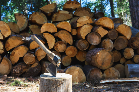 Old axe standing against a piled pieces of firewoodの写真素材