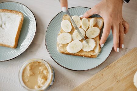 women's hands cut a sandwich with peanut paste and bananaの写真素材