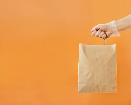 Ð¡oncept of safe home delivery in a pandemic. Coronavirus 2019-nCov Protection. Courier Paper bag hand in protective glove. Copy space.の写真素材