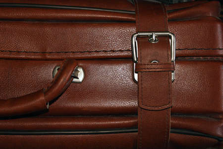 Dusty brown suitcase with clasp as a background illustration of a day of travel.
