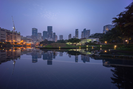 Kuala Lumpur, Malaysia - September 7, 2015: Hazy sunrise at Kuala Lumpur City Centre as seen from Symphony Lake Park, Suria KLCC with reflection on the lake.のeditorial素材
