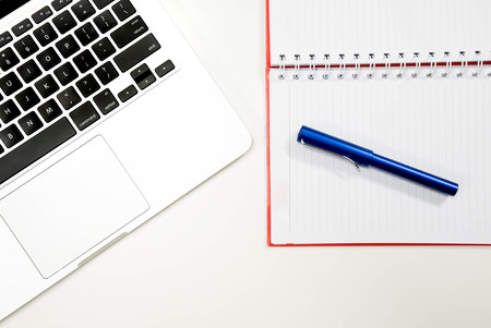 Flat lay photo of white office desk with laptop keyboard, top view