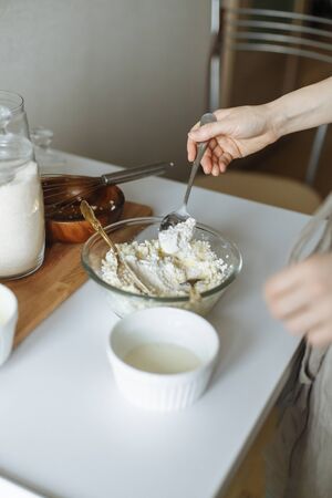 female hand prevents a golden.fork with a white cup on a white table cottage cheese in a cupの写真素材