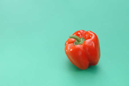 Fresh, red, bell pepper on a turquoise plain background.の写真素材