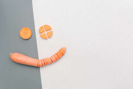 Carrot slices in the form of a smiling face on a gray-light background.の写真素材