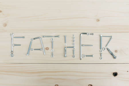 The inscription father on a wooden table consisting of nuts and bolts.