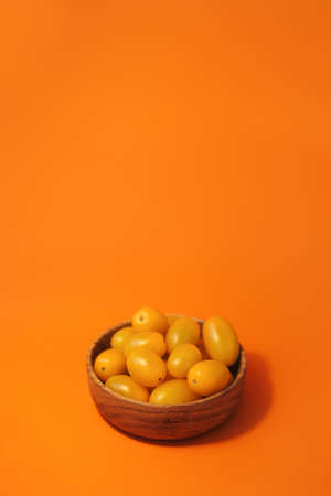 Juicy, tasty yellow tomatoes on a bright orange background, full screen.の写真素材